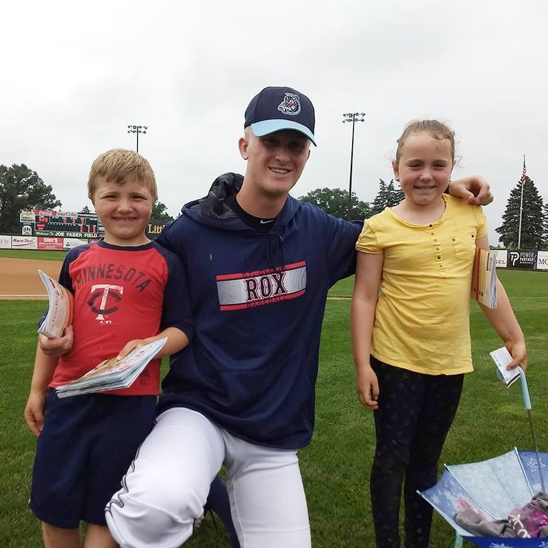 Baseball player posing with children