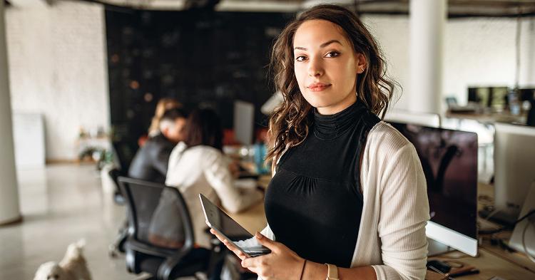 A female entrepreneur in the office, with employees behind her 