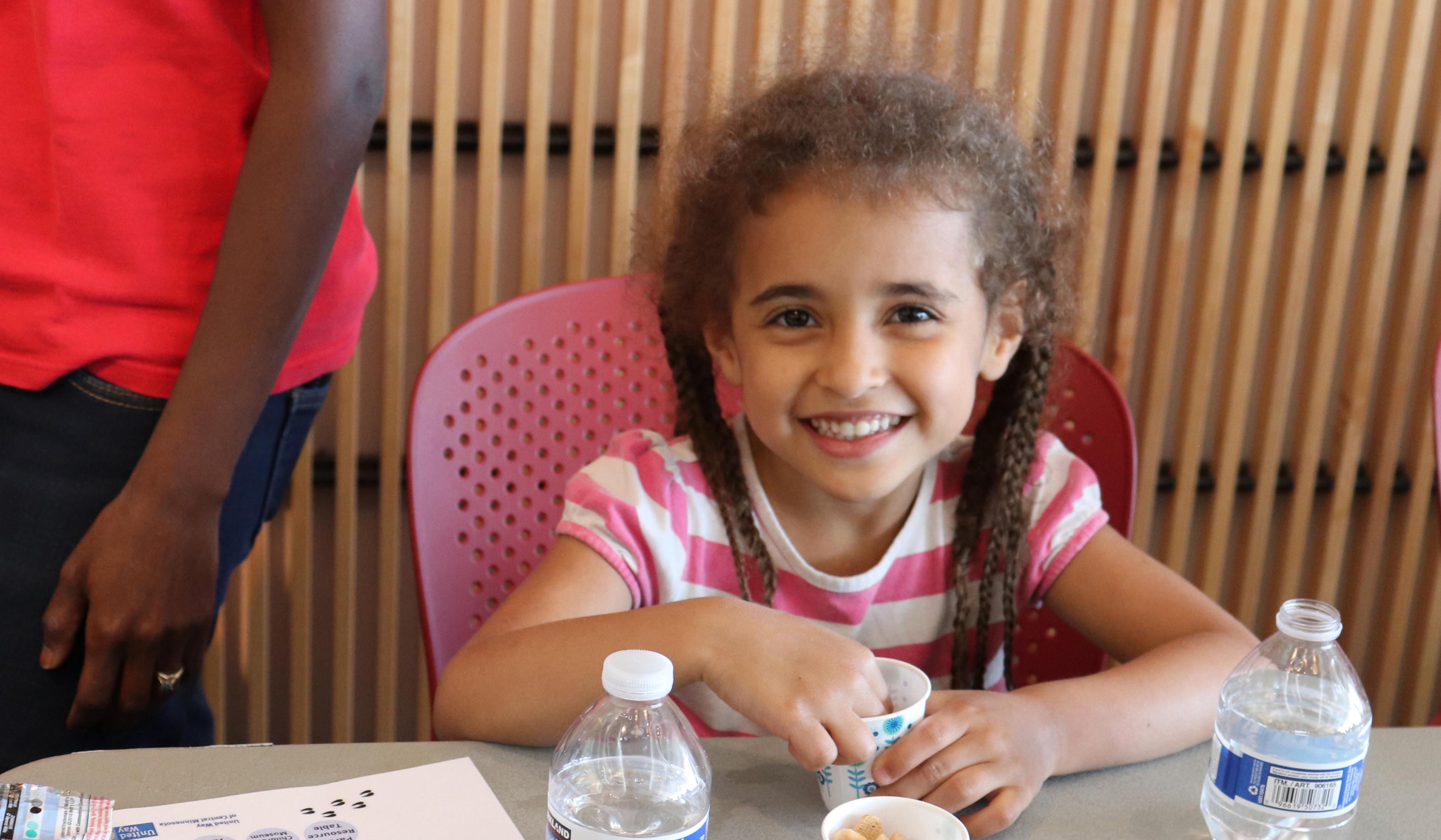 Little girl with braids eats a snack at Llama Llama Read-A-Rama event