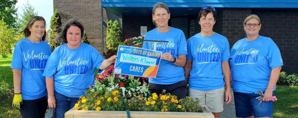 5 volunteers outside around a flower planter